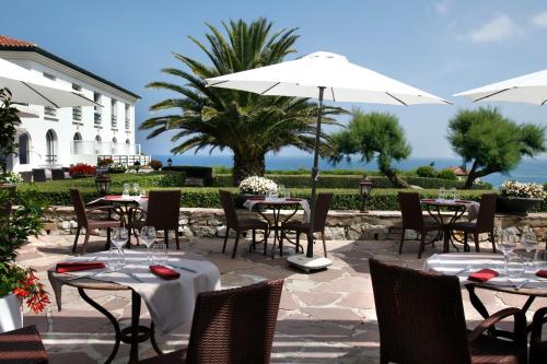 a restaurant with tables and chairs and an umbrella at Hôtel La Réserve in Saint-Jean-de-Luz