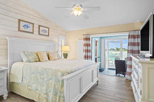 Un dormitorio con una cama y un televisor y un balcón. en Infinity & Beyond Lake Front, en Cabo Coral