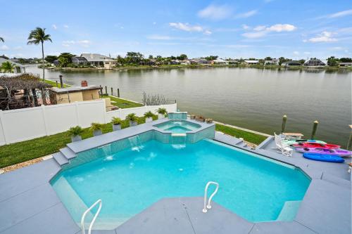a swimming pool next to a body of water at Infinity & Beyond Lake Front in Cape Coral