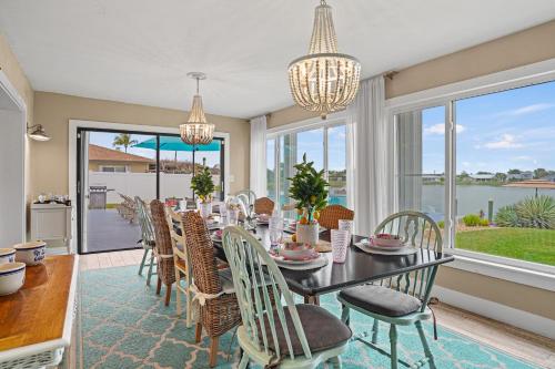 a dining room with a table and chairs and windows at Infinity & Beyond Lake Front in Cape Coral
