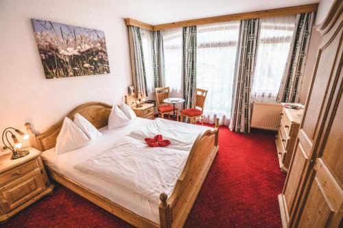 a bedroom with a bed with a red bow on it at Hotel Metzgerwirt in Kirchberg in Tirol