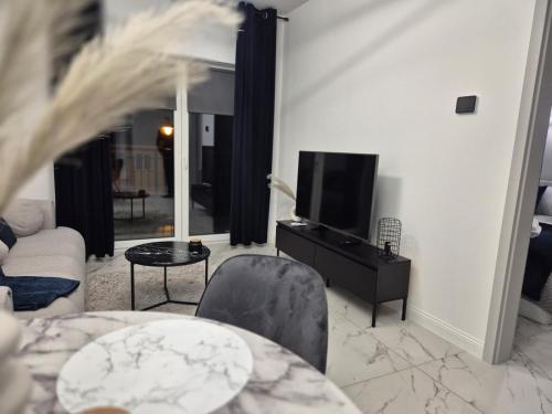 a living room with a tv and a couch and a table at Apartament BalticSea 12 Mielno in Mielno
