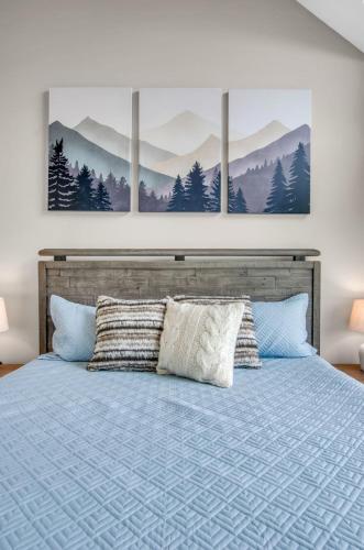 a bedroom with a bed with three paintings on the wall at Family townhouse with Fireplace in Ellicottville