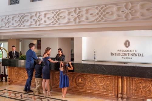 a group of people standing at a counter in a lobby at Presidente InterContinental Puebla by IHG in Puebla