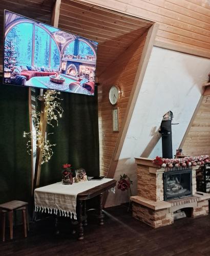a living room with a fireplace and a large screen at Koka namiņš "Pasaka" in Vecumnieki
