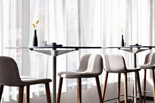 a glass table with four chairs and vases on it at AC Hotel by Marriott Grand Rapids Downtown in Grand Rapids
