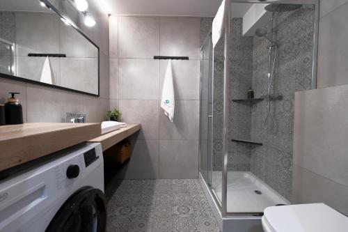 a bathroom with a shower and a washing machine at Laguna Beskidów Resort - Apartament Simple Comfort in Zarzecze