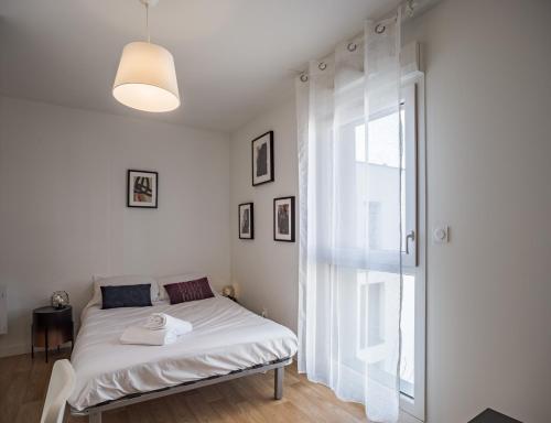 a white bed in a room with a window at Le Cocon de l'Artiste - moderne, artistique et cosy ! in Troyes