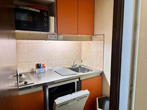 une petite cuisine avec un évier et un micro-ondes dans l'établissement Résidence Le Tourmalet - maeva Home - Studio 4 personnes - Confort MAE-8071, à La Mongie