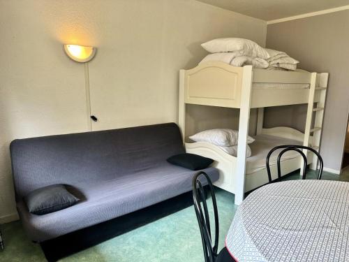 Cette petite chambre comprend des lits superposés et une table. dans l'établissement Résidence Le Tourmalet - maeva Home - Studio 4 personnes - Confort MAE-8071, à La Mongie