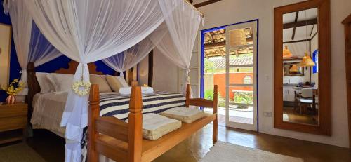 a bedroom with a canopy bed with white curtains at Suíte Kuta - Buddha House in Ilhabela