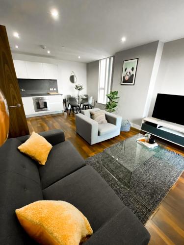 a living room with a black couch and a table at The Panda - Modern 2 Bedroom Apt in Manchester City Centre in Manchester