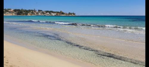 a beach with the ocean and a city in the background at Shati Luxury - New, Heated Pool, Sea view Near beach in Fontane Bianche