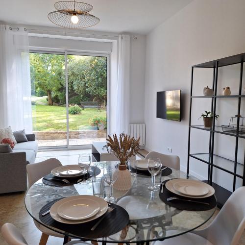 une salle à manger avec une table et des chaises en verre dans l'établissement Appart chic-calme rdc avec jardin, à Mayenne