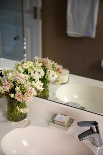 a bathroom sink with flowers in a mirror at Lemoenkloof Boutique Hotel in Paarl