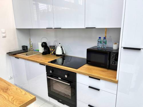 a kitchen with white cabinets and a black microwave at LUMAX Studio in Gryfice