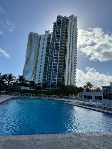 a large swimming pool in front of tall buildings at Miami Sunny Isles Beach Ocean Front Resort Condo with balcony Pool, Beach,Gym,Valet Parking in Sunny Isles Beach