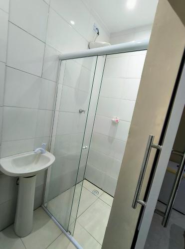 a bathroom with a glass shower and a sink at Pousada chc in Praia Grande