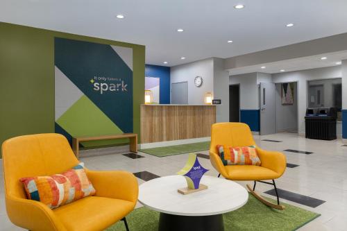 a waiting room with two chairs and a table at Spark By Hilton Evansville East, In in Evansville