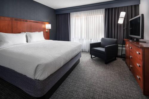 a hotel room with a bed and a chair at Courtyard by Marriott Pleasanton in Pleasanton