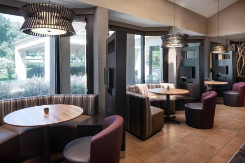 a restaurant with tables and chairs and windows at Courtyard by Marriott Pleasanton in Pleasanton