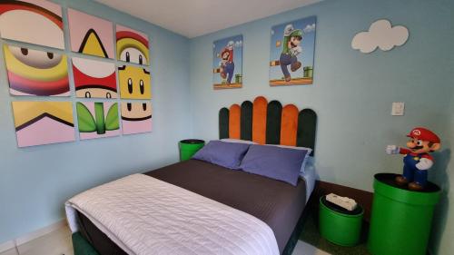 a bedroom with a bed and paintings on the wall at Departamento Zona Gamer Frente al Aeropuerto in Mexico City