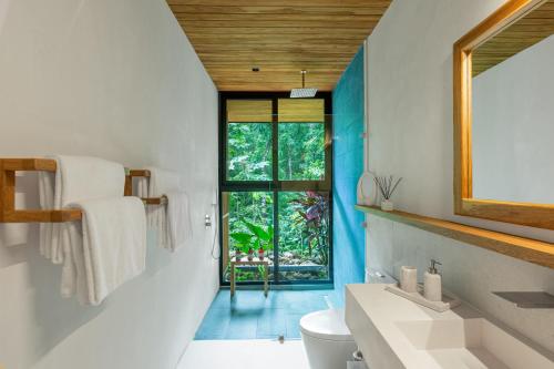 a bathroom with a white toilet and a window at Villa Koa - Your Tropical Retreat in Santa Teresa Beach
