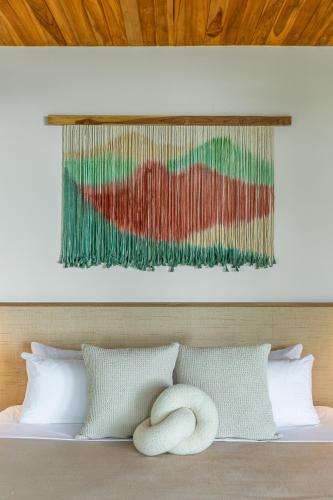 a bed with two pillows and a painting on the wall at Villa Koa - Your Tropical Retreat in Santa Teresa Beach