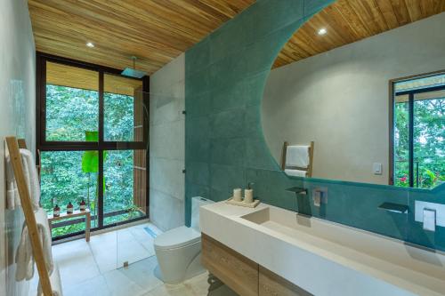 a bathroom with a sink and a toilet and a window at Villa Koa - Your Tropical Retreat in Santa Teresa Beach