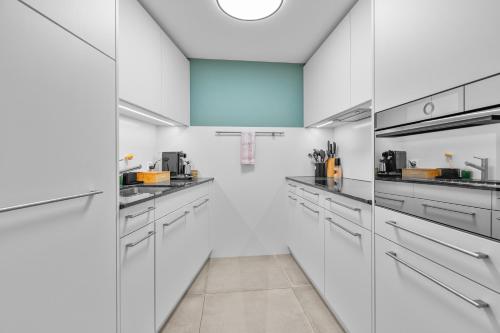 a white kitchen with white cabinets and appliances at Gemütliche 2.5 Zimmer Wohnung mit privater Sauna in Seewis im Prättigau