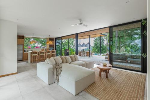 a living room with a white couch and a kitchen at Villa Koa - Your Tropical Retreat in Santa Teresa Beach