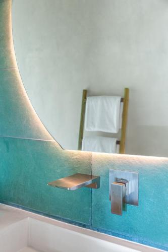 a mirror above a sink in a bathroom with a chair at Villa Koa - Your Tropical Retreat in Santa Teresa Beach