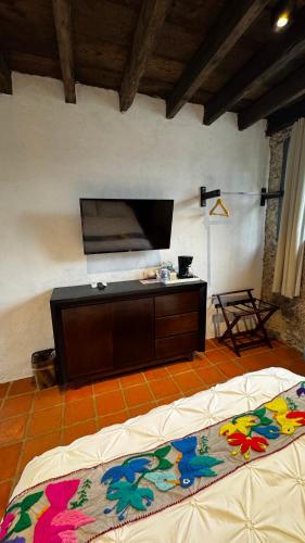 a room with a bed and a tv on the wall at La Peña Hotel Boutique & SPA in Cuetzalán del Progreso