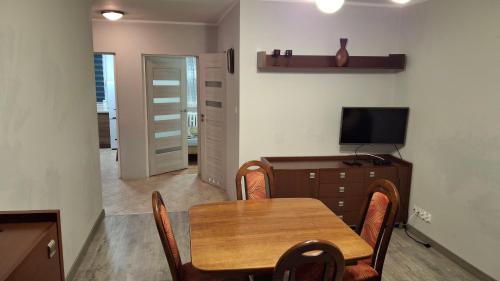 a dining room with a wooden table and a television at Mieszkanie 2-pokojowe 40 m2 blisko centrum in Starogard Gdański