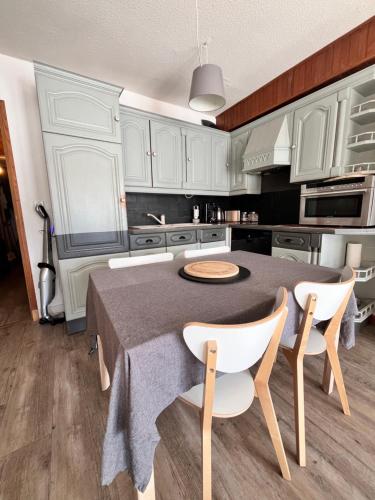 une cuisine avec des armoires blanches et une table et des chaises dans l'établissement Terrasse, vue imprenable et accès direct pleine nature, votre refuge idéal, à Orcières
