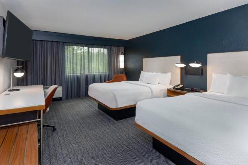 a hotel room with two beds and a desk at Courtyard Tallahassee North/I-10 Capital Circle in Tallahassee