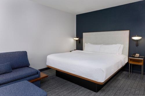 a bedroom with a bed and a blue chair at Courtyard Tallahassee North/I-10 Capital Circle in Tallahassee