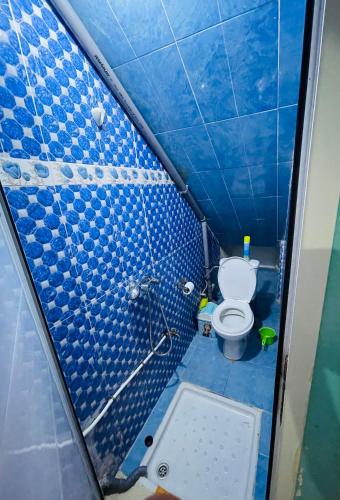 a bathroom with a toilet and a blue tiled wall at fulki house in Taghazout