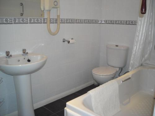 a white bathroom with a sink and a toilet at Townstal Farmhouse in Dartmouth