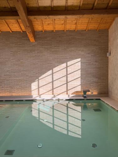 an empty swimming pool with a shadow of a building at Villa Petriolo - Small Luxury Hotels of the World in Cerreto Guidi
