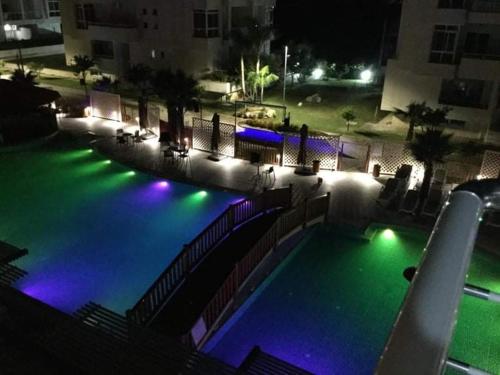 a swimming pool at night with green and blue lights at JL apartament tirana resort in Radhimë