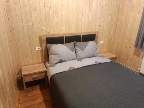 a bed in a room with wood paneled walls at Casa La Măriuca in Bran