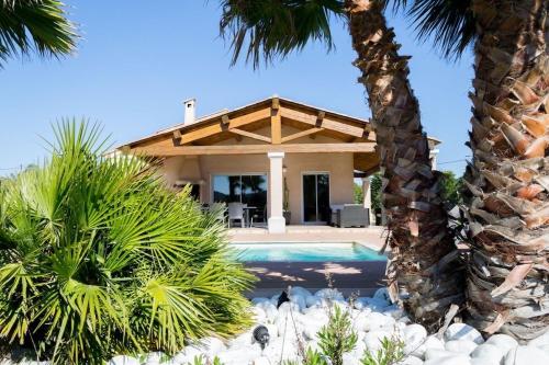 une maison avec une piscine et des palmiers dans l'établissement Le Mas des Vignes, à Ramatuelle