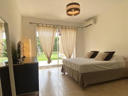 une chambre avec un lit et une grande fenêtre dans l'établissement Le Mas des Vignes, à Ramatuelle