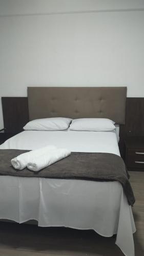 a bed with white sheets and pillows on it at Apartamento completo B51,com ar condicionado,400 m do centro in Mogi das Cruzes