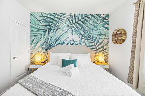 a bedroom with a white bed with a tropical leaf wallpaper at Large Pool, Near the Beach, 5 Bedroom, King Beds, Patio, Grill, Pet Friendly in Corpus Christi