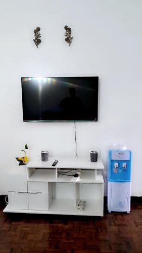 a white entertainment center with a flat screen tv on a wall at Gia Apartment in Shanzu