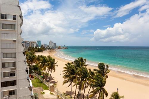 a view of a beach with palm trees and a building at Courtyard by Marriott Isla Verde Beach Resort in San Juan