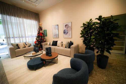 a living room with a christmas tree and blue chairs at Hotel Dan Inn Poços de Caldas - A melhor localização do Centro by Nacional Inn in Poços de Caldas