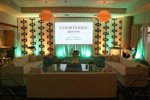 a stage with couches and a screen with a sign at Courtyard by Marriott Isla Verde Beach Resort in San Juan